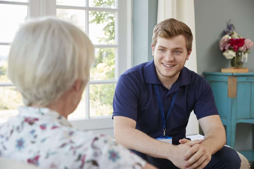 Senior woman talking with male care worker on home visit Senior woman talking with male care worker on home visit