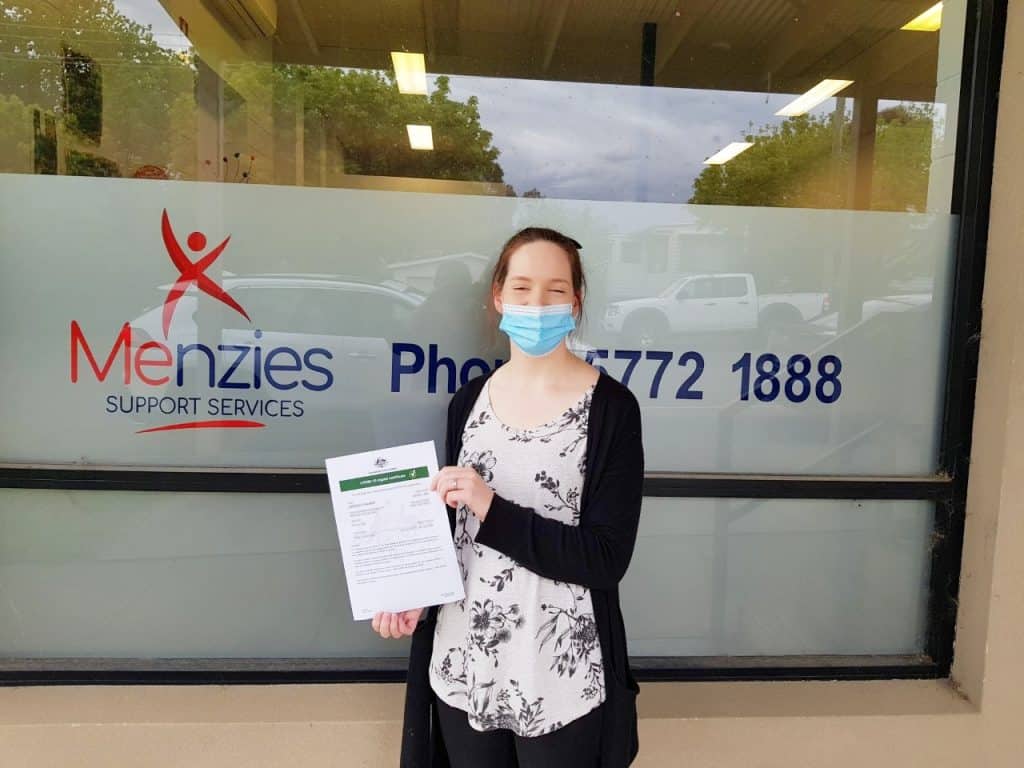 Jess, Disability Services Assistant, has received both doses of vaccine. Jess is pictured with a printout of her digital certificate.